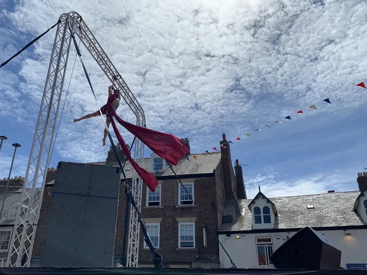 An aerial silks performer high above Front Street during the free daytime programme at a previous festival