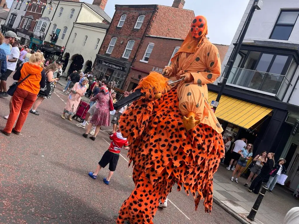 A stilt-walking performer in a bird costume on Front Street at a previous Mouth of the Tyne Festival
